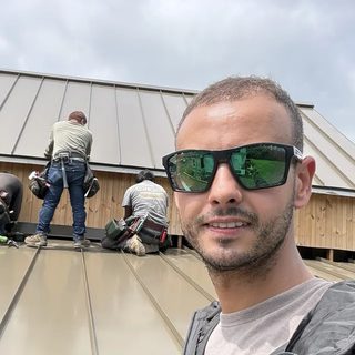 Sultan El Jabali, owner of ALFE Roofing, on a standing seam roof with a roofing crew